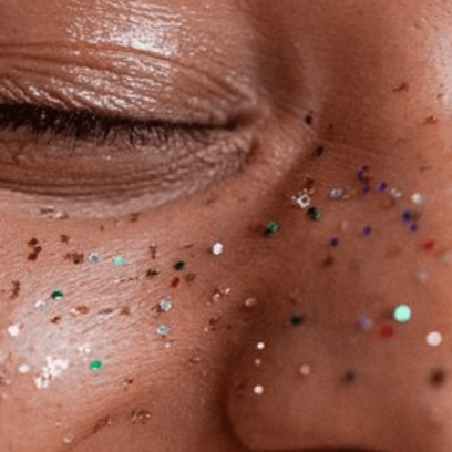 Women smiling with rainbow glitter on her face