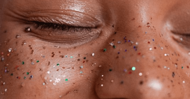 Women smiling with rainbow glitter on her face