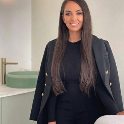 Young skin specialist poses next to beauty treatment table in her salon