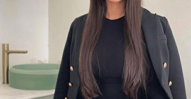 Young skin specialist poses next to beauty treatment table in her salon
