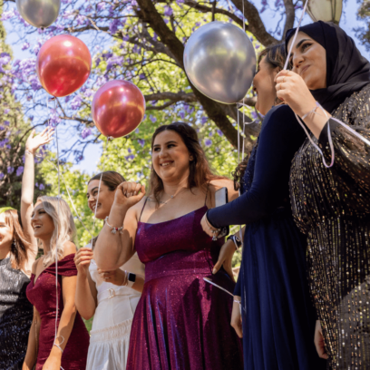 students at graduation holding balloons in a park