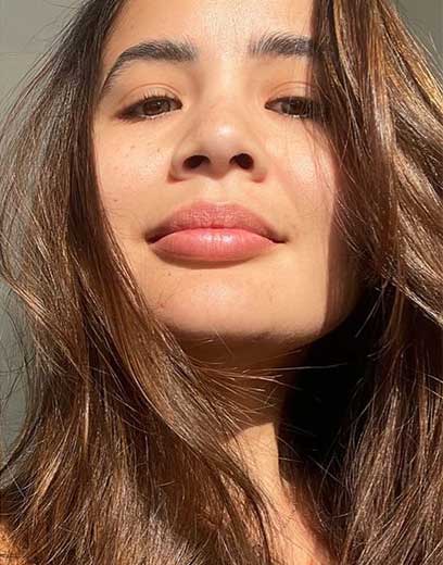 A picture of a beautiful southeast asian woman with glowing skin and shiny brunette hair in direct sunlight