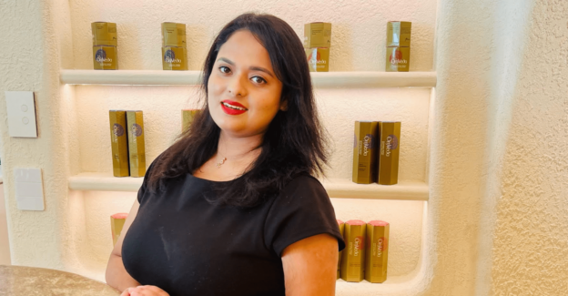 Lady wearing a black top with red lipstick in front of beauty products