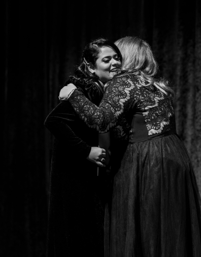 Two women hugging on stage at graduation