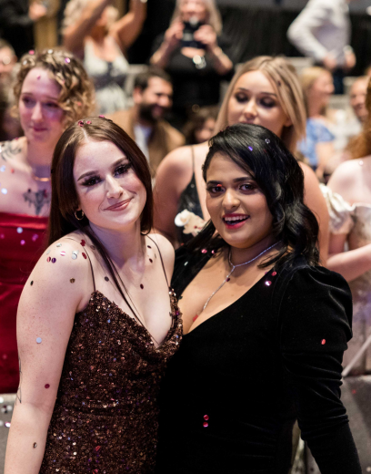 Two friends smiling at graduation in formal gowns