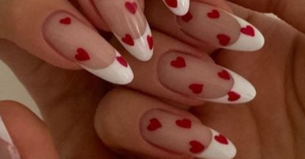 An elegant French manicure with red heart nail art for Valentines day