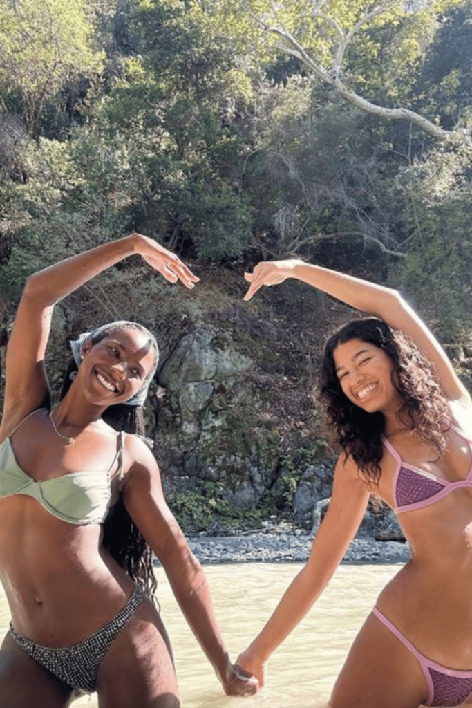 Two best friends on the beach making the shape of a heart with their hands