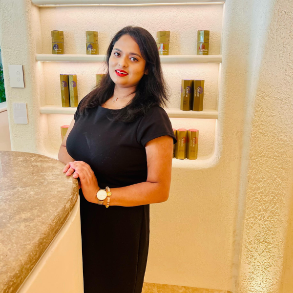 Lady wearing a black top with red lipstick in front of beauty products